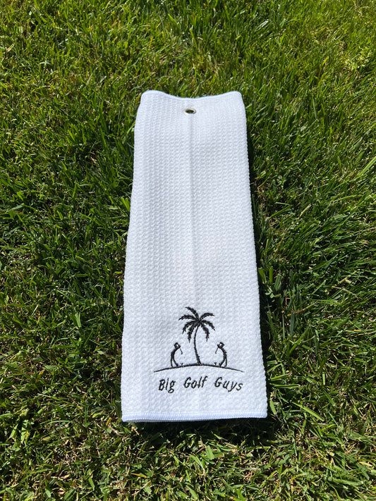 gray waffle towel with black big golf guys logo grass background
