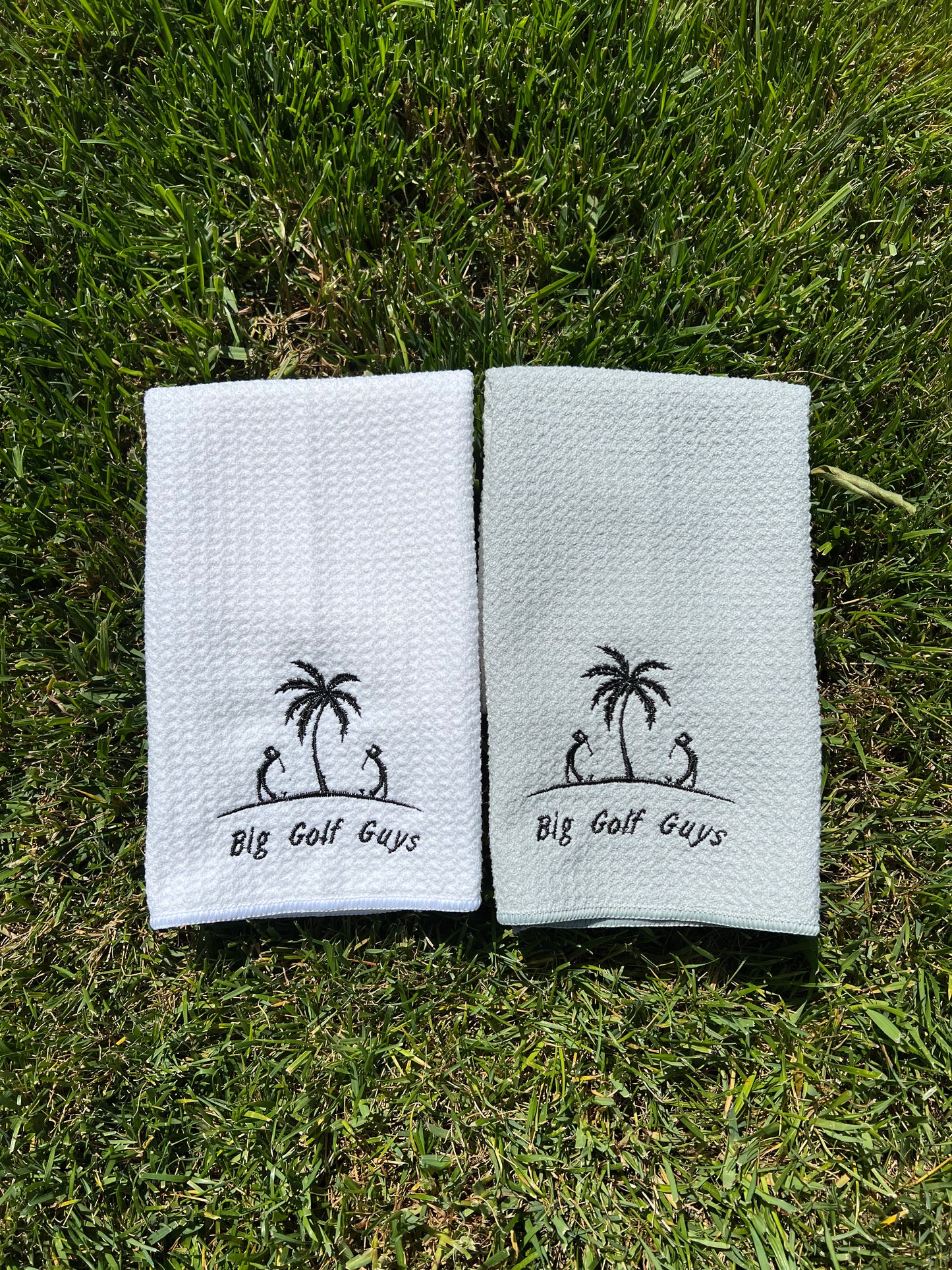 Side by side folded waffle towels gray and white, black big golf guys logo